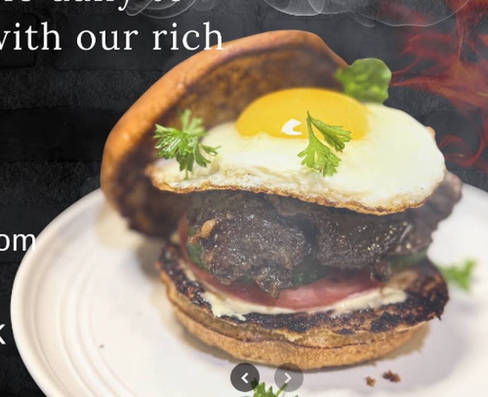 A crispy pork belly sandwich with a sunny-side egg on a white plate